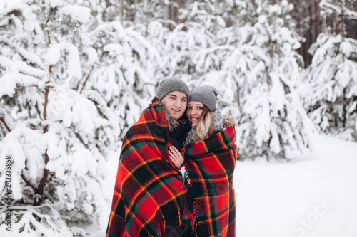 Embracing couple looking at camera with smiles in winter park
