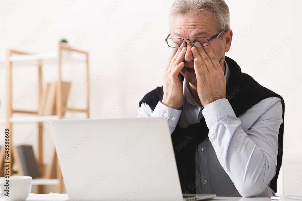 Hard day. Elderly man feeling tired, working on laptop Hard day. Elderly man feeling tired, working on laptop