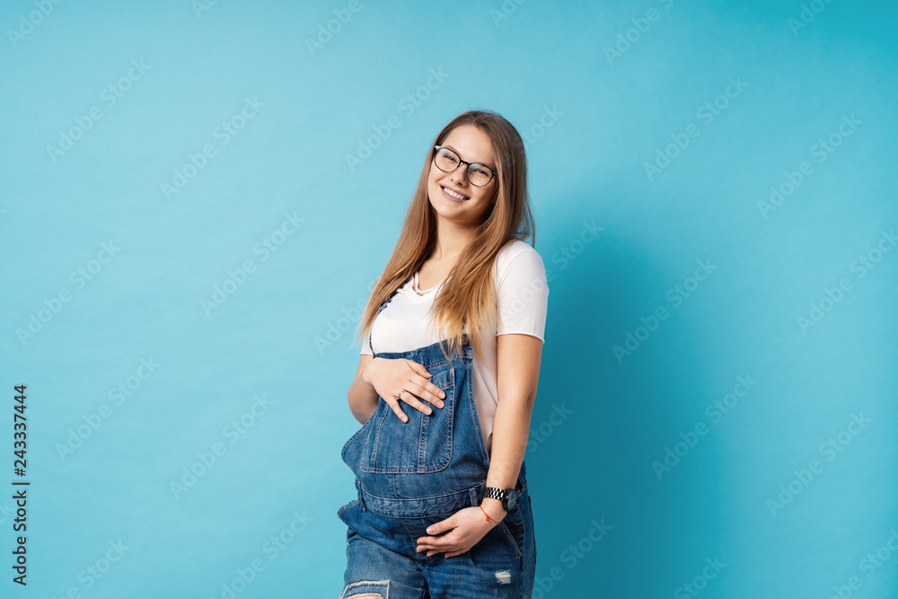 Smiling pregnant woman wearing glasses caressing her belly over Smiling pregnant woman wearing glasses caressing her belly over