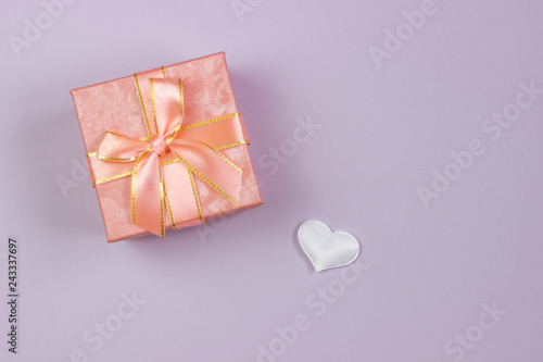 A gift in a beautiful box and a white heart on a pink background. Valentine's Day, International Women's Day. © Denis