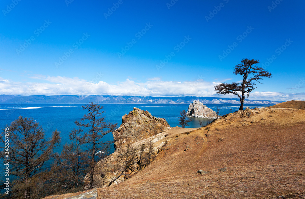 Fototapeta premium Lake Baikal. Olkhon Island in May day. View of the Small Sea Strait, the famous Shamanka Rock and the tree of desires on a sunny day. Beautiful spring landscape
