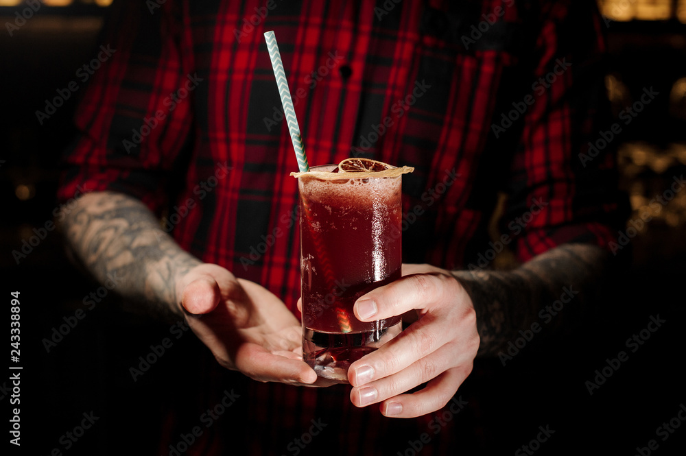Barman holding a glass of cold fresh juicy berry alcoholic cocktail