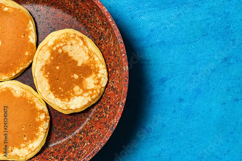 Ruddy and lush pancakes on a stone pan. Granite pan with baking on blue background