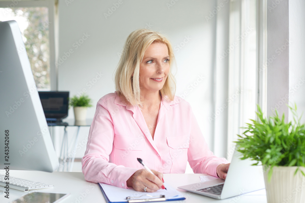 Senior professional woman sitting at office desk and working Senior professional woman sitting at office desk and working