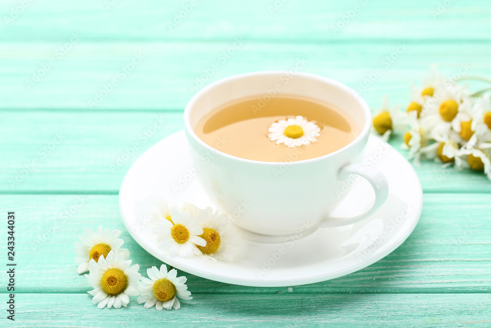 Cup of tea with chamomile flowers on mint wooden table Cup of tea with chamomile flowers on mint wooden table