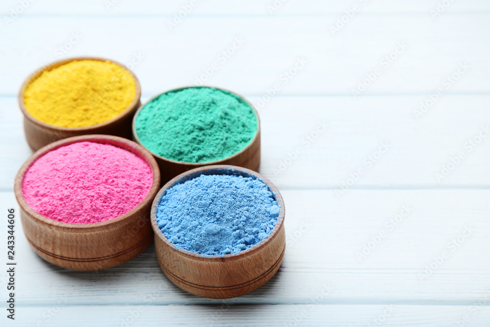 Colorful holi powder in bowls on wooden table Colorful holi powder in bowls on wooden table