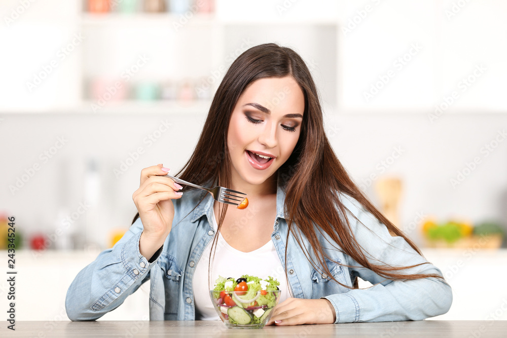 Beautiful woman eating fresh salad in the kitchen Beautiful woman eating fresh salad in the kitchen