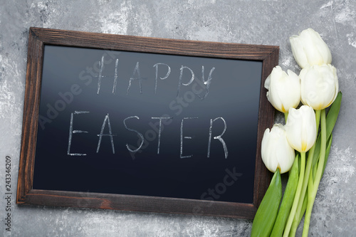 Inscription Happy Easter on wooden frame with white tulips