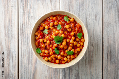Spicy Chickpea curry Chana Masala in bowl on wooden table. Traditional Indian dish. Top view. Copy space.