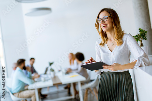 Elegant businesswoman standing in office with digital tablet photo