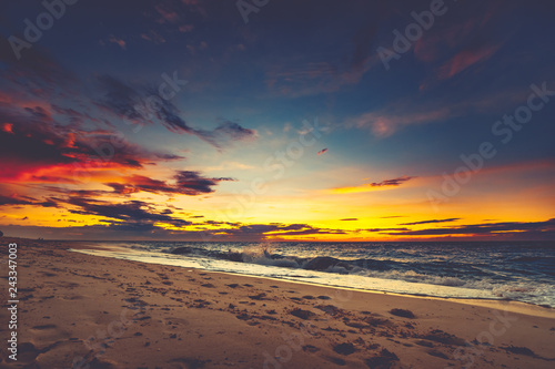 Bright sunset over the Asian shoreline. Stunning landscape. Breathtaking cloudy colorful sky over the ocean and the beach. The footprints on the sand surface. Ideal image for the backgrounds. © Goinyk