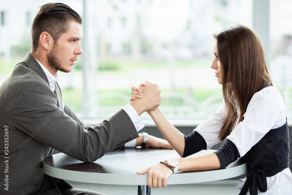 business and office concept - businesswoman and businessman arm wrestling during meeting in office. business and office concept - businesswoman and businessman arm wrestling during meeting in office.