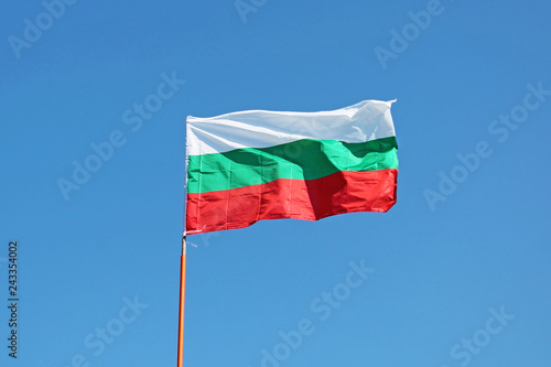Waving Flag of Bulgaria on blue sky background close up. 