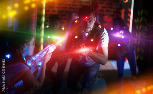 Emotional guy playing laser tag in colorful beams