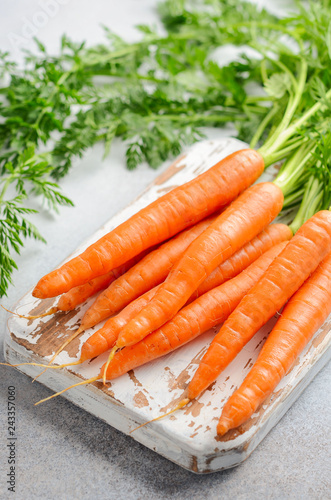 Bunch of fresh carrots on wooden cutting board.