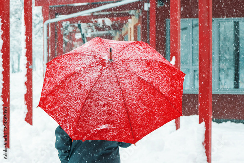 Sad and alone woman walking in snow through urban environment