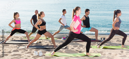 Sporty people practicing yoga on beach