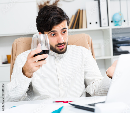 Manager with glass of wine having online conversation