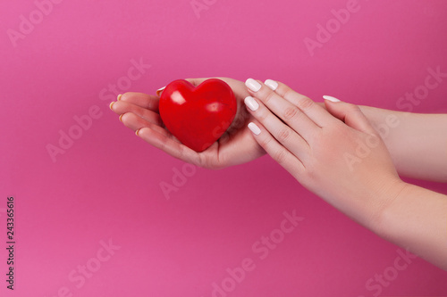 People, relationship and love concept - close up of womans cupped hands showing red heart