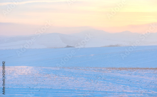 Sunset over hills covered with snow