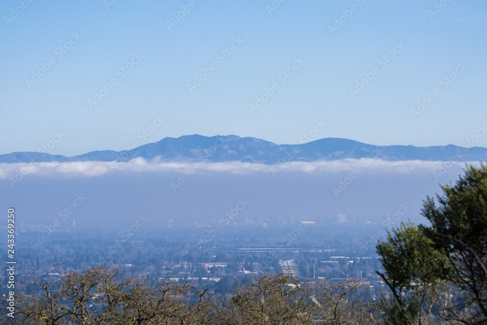 View towards Mt Hamilton summit (and the observatories) in Diablo mountain range; Cupertino and San Jose downtown visible below a layer of clouds; Silicon Valley; south San Francisco bay California