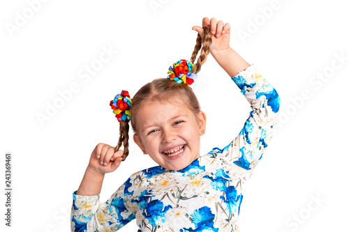 Studio waist up portrait of a little girl wearing shirt with a print and with two pigtails and color bows on a gray background.