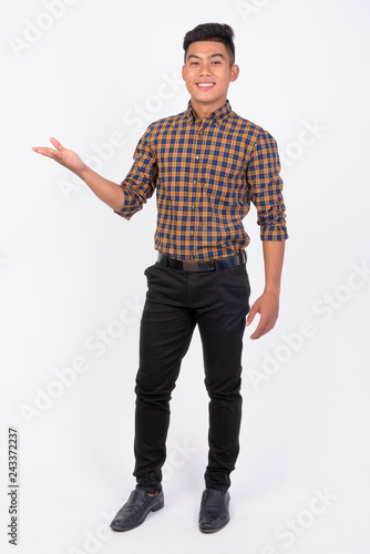 Young happy Asian businessman showing something against white background