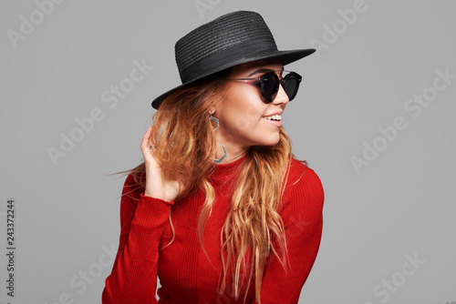 Fashion portrait pretty woman in black rock style hat and sunglasses over grey background. Holiday concept