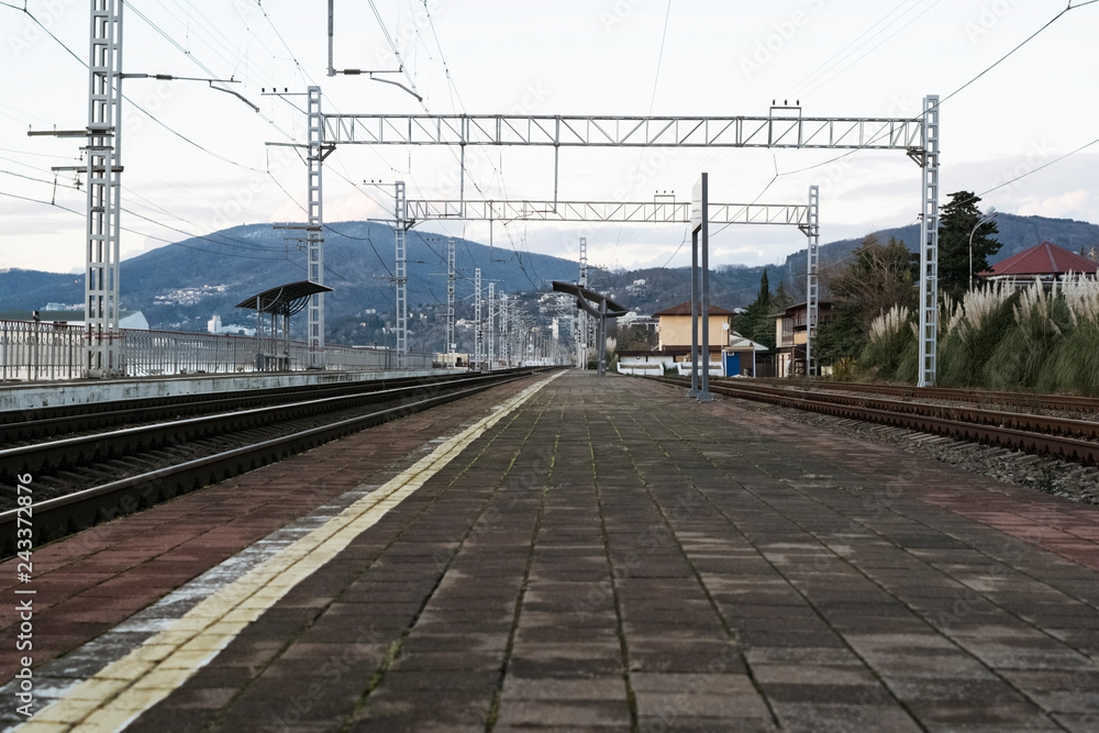 Empty railway station by the sea against the mountain in the evening twilight