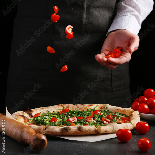 pizza preparation with chef hands. pizza making process decoroting pizza on black background