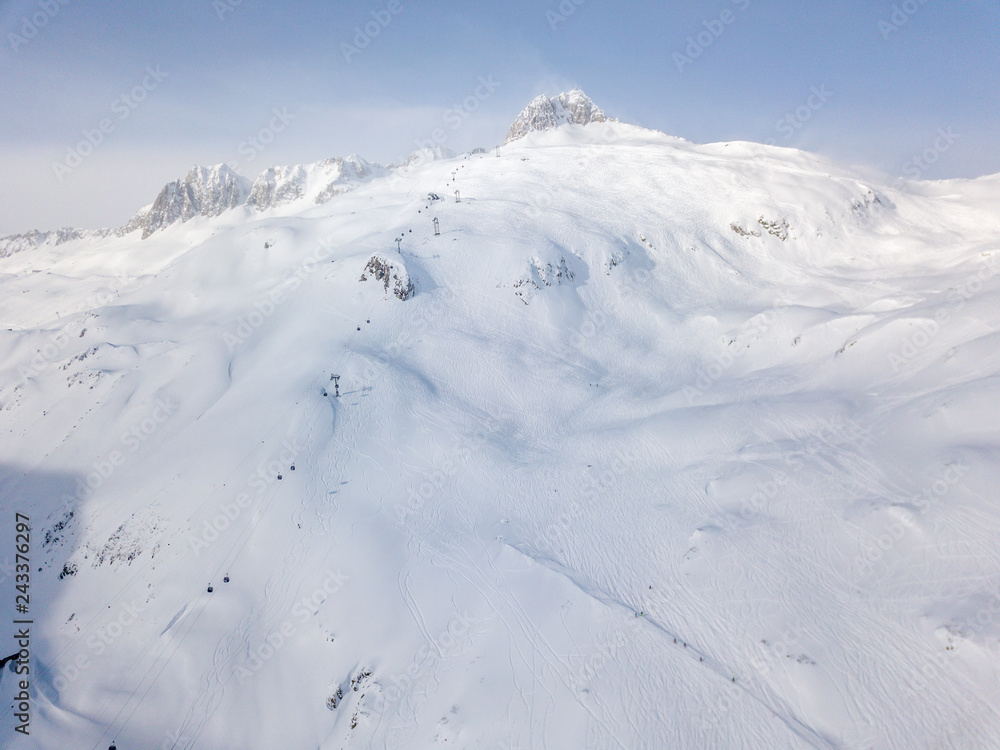 Aerial view of snow covered terrain in mountain area. Mountains in central Switzerland. Alps with snow in beautiful light with shadow and sun.