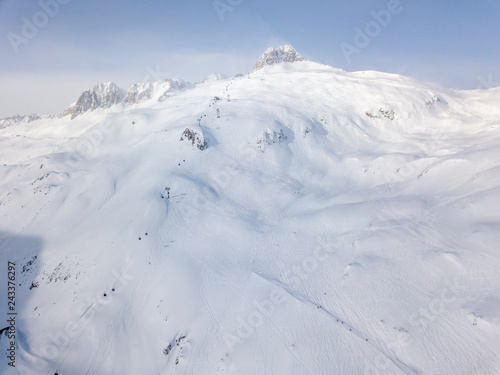 Aerial view of snow covered terrain in mountain area. Mountains in central Switzerland. Alps with snow in beautiful light with shadow and sun. © Mario