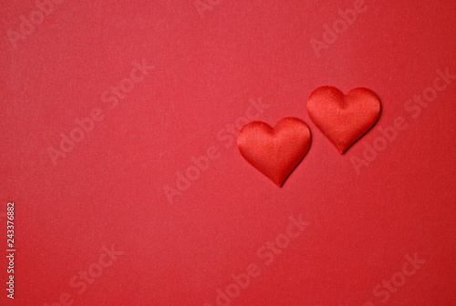 Two red hearts for Valentine's Day love on a red paper background