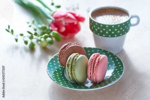 Spring coffee background. Pink tulip, freesia, espresso and macarons with spring flowers