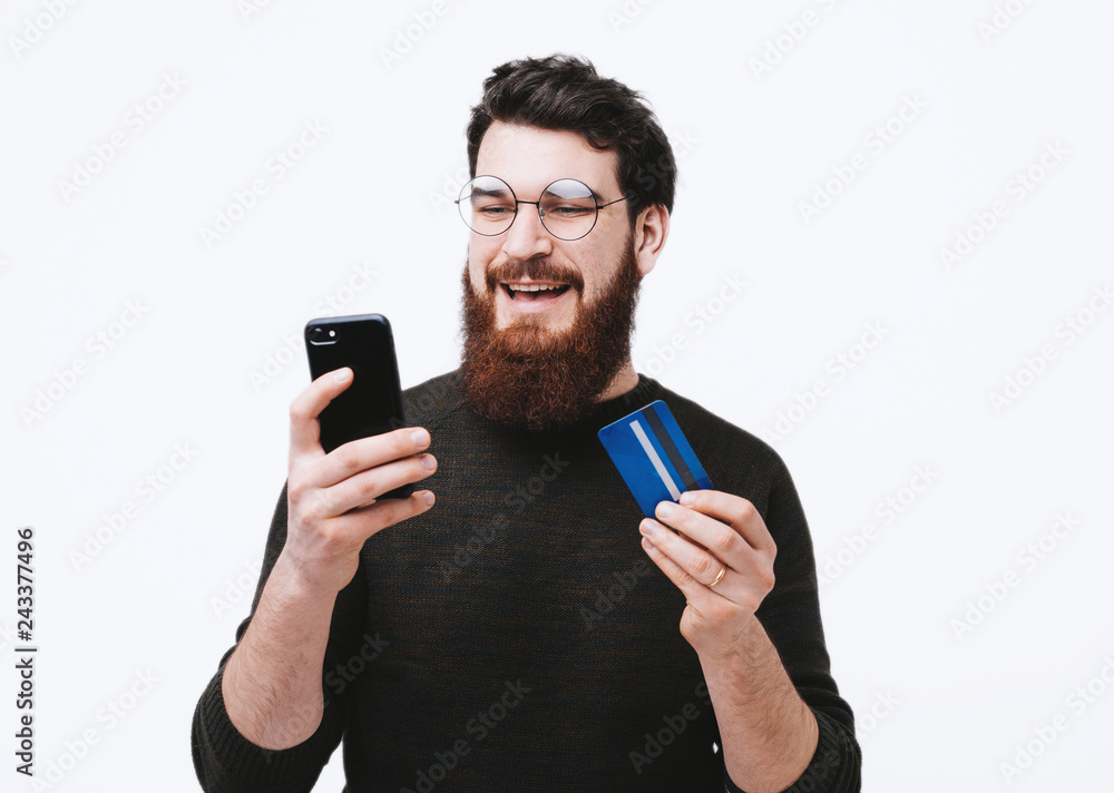 Happy smiling guy with credit car in hand is shopping oline Happy smiling guy with credit car in hand is shopping oline