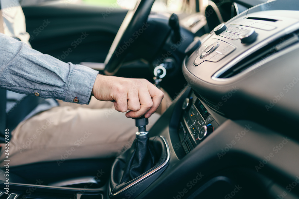 Close up of Caucasian man holding hand on gearshift.
