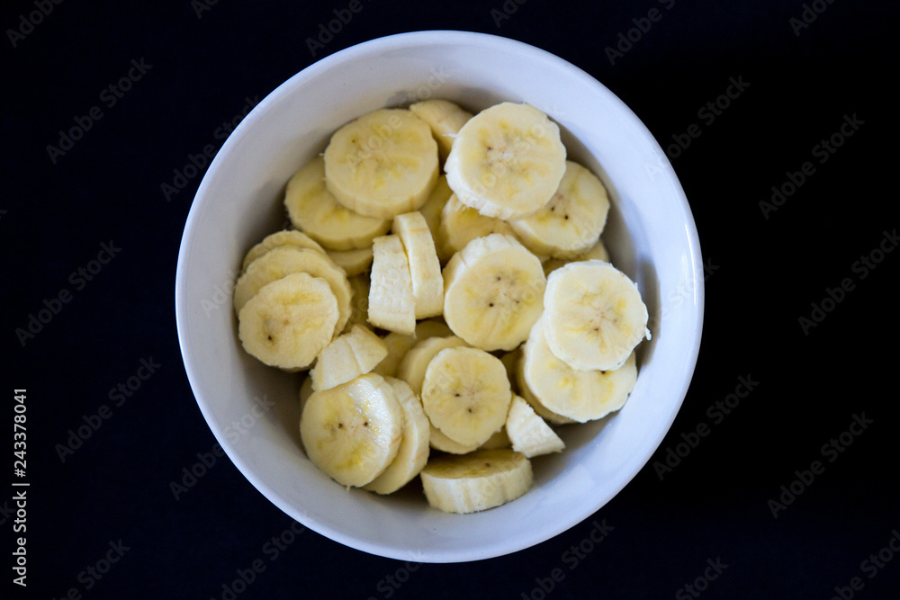 Banana prata picada em tigela branca, com fundo preto. Banana prata picada em tigela branca, com fundo preto.