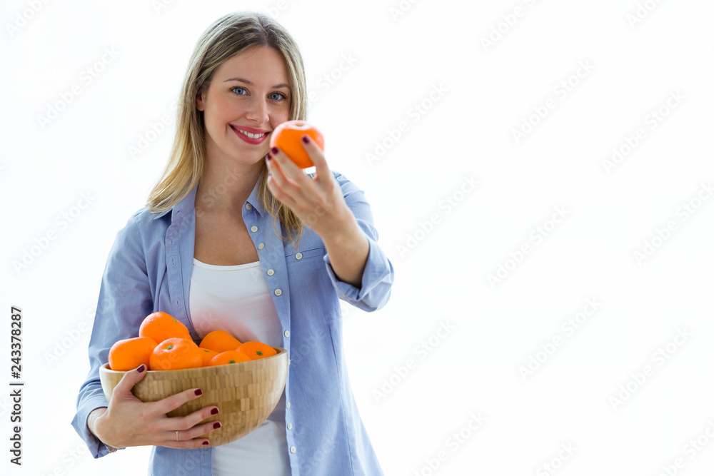 Pretty young woman showing orange to camera while holding a bowl over white background. Pretty young woman showing orange to camera while holding a bowl over white background.