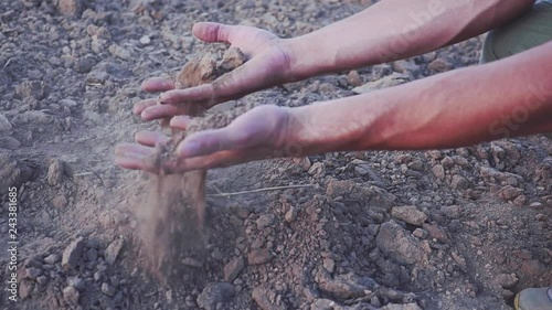 The hands of the young farmer keep fertile soil on the field. Organic Products Concept. slow motion