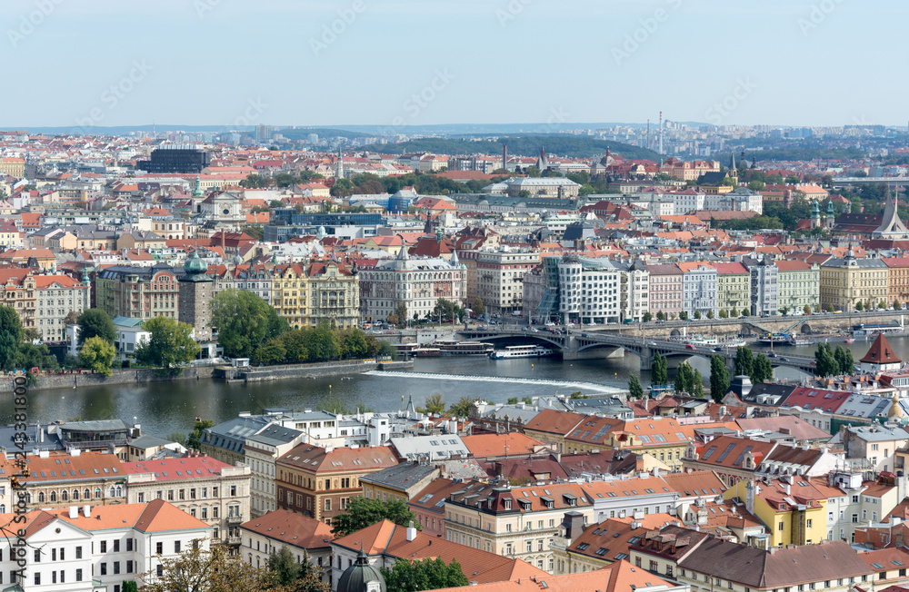 Prague panorama with colorful rooftops, row of Vltava river waterfront buildings and Dancing house in view