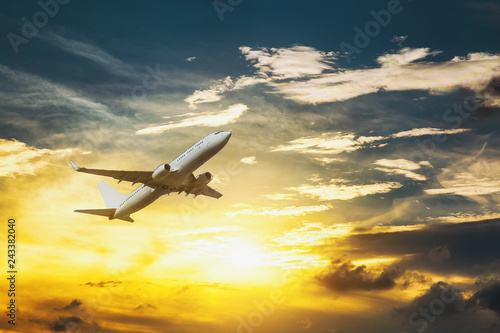 White passenger double decker plane in flight high above the golden clouds during the sunset.