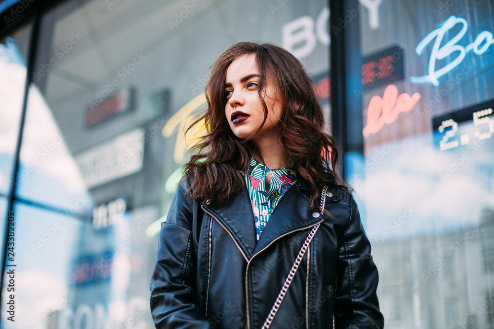 Fashion hipster woman posing outdoor. leather jacket brunette hair