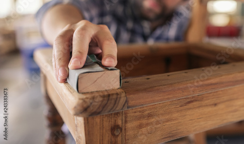 Closeup of craftsman sanding a chair in his workshop