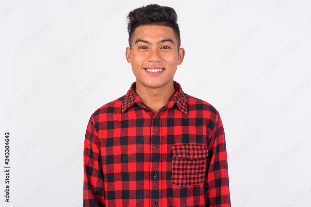 Young happy Asian hipster man smiling against white background Young happy Asian hipster man smiling against white background