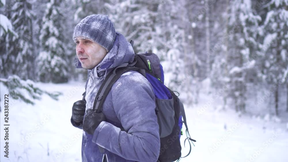 stern frozen man in the cold winter goes through the woods with a backpack stern frozen man in the cold winter goes through the woods with a backpack