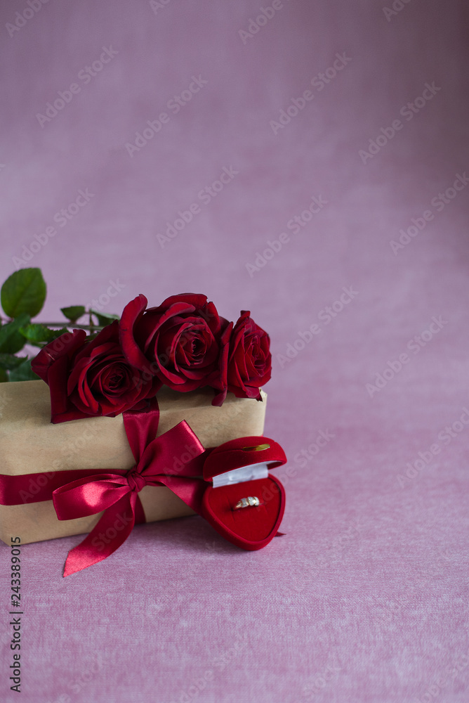 red roses on a gift box, a box with a ring lies on a pink background, flowers, a gift and a ring on a pink background, a proposal to get married (vertically, copy space) red roses on a gift box, a box with a ring lies on a pink background, flowers, a gift and a ring on a pink background, a proposal to get married (vertically, copy space)