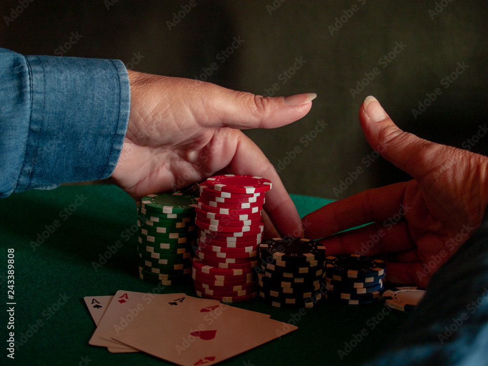 A person playing poker with the four aces of a deck in his hand and poker chips of various colors on a green mat A person playing poker with the four aces of a deck in his hand and poker chips of various colors on a green mat