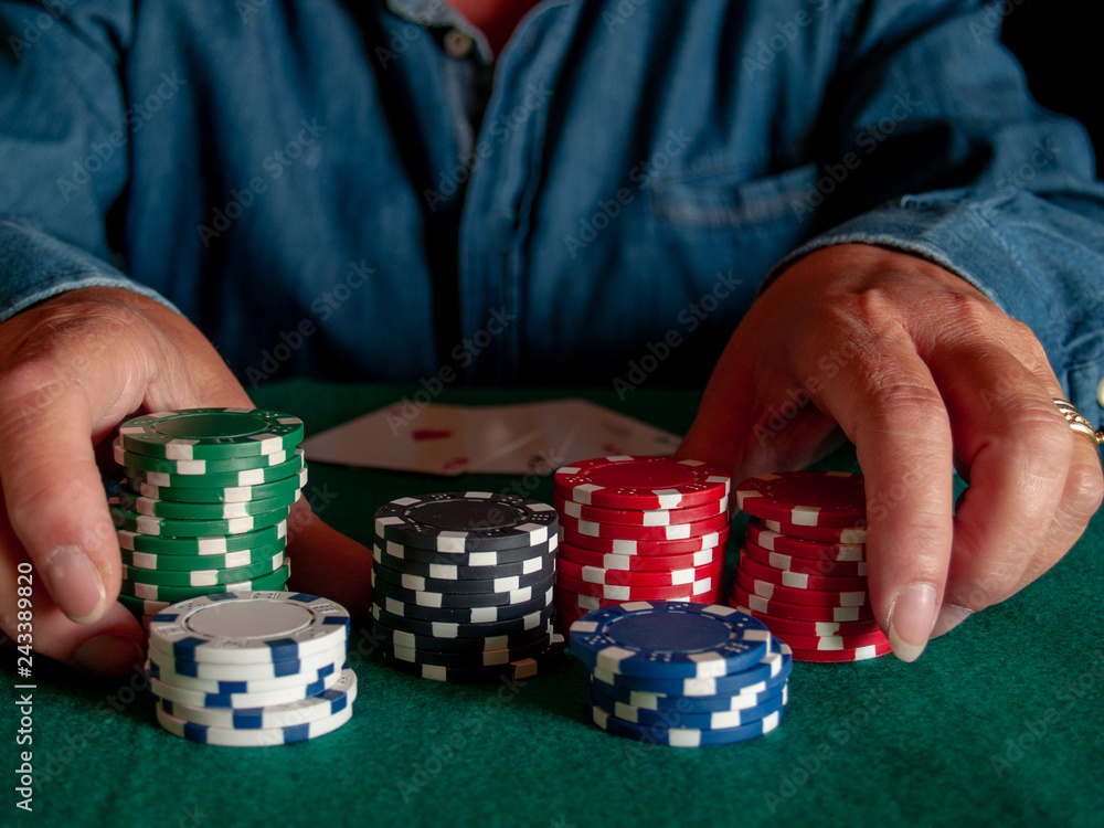 A person playing poker betting poker chips of various colors A person playing poker betting poker chips of various colors