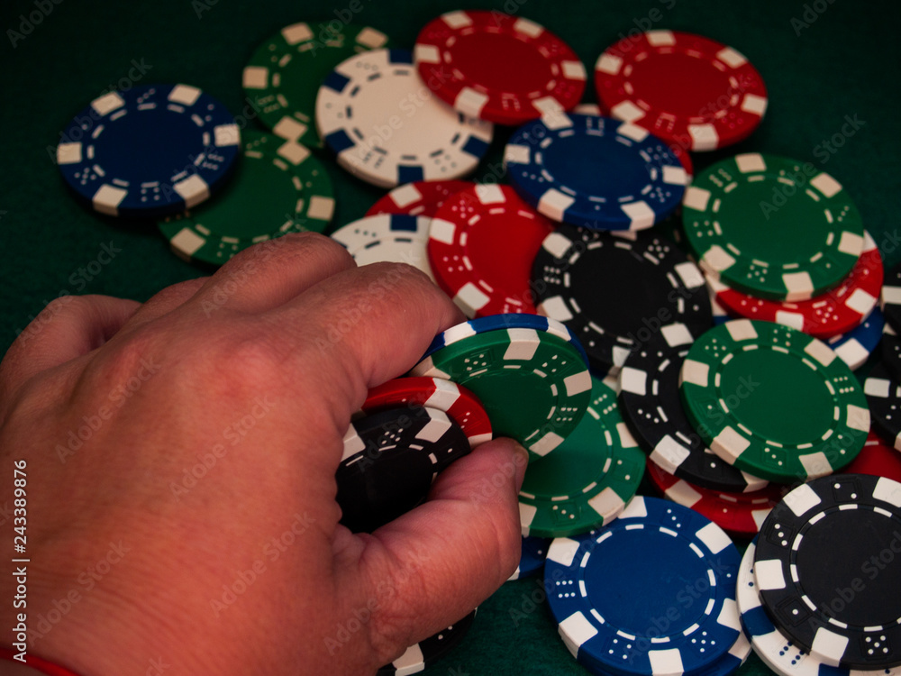 A person holding poker chips of various colors with his hand A person holding poker chips of various colors with his hand