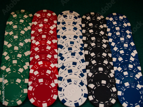 Poker chips of various colors on a green mat